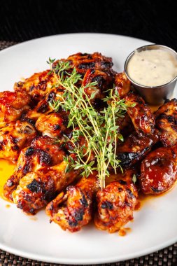 Meksika mutfağı, tartar sos ile beyaz tabakta kekik ile sırlı sıcak yağda kızarmış tavuk kanatları. kavram güzel restoranda servis yapın. Foton görüntü.