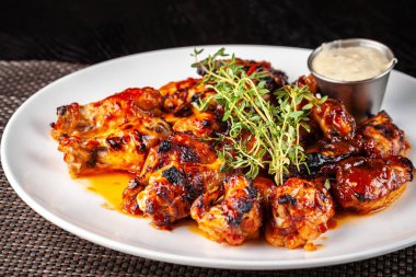 Meksika mutfağı, tartar sos ile beyaz tabakta kekik ile sırlı sıcak yağda kızarmış tavuk kanatları. kavram güzel restoranda servis yapın. Foton görüntü.