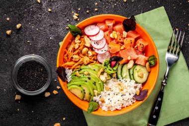 Hawaiian salata somon balık, avokado, Kore havuç, salatalık, turp ve pirinç siyah susam ile Poke. turuncu bir tabak içinde. Siyah arka plan üzerine. kopya alanı, üstten görünüm