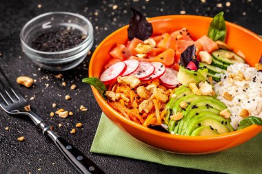 Hawaiian salata somon balık, avokado, Kore havuç, salatalık, turp ve pirinç siyah susam ile Poke. turuncu bir tabak içinde. Siyah arka plan üzerine. kopya alanı, üstten görünüm