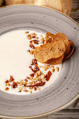 Kurutulmuş domates ve çam fıstığı ile İtalyan peynir krem çorbası. Tablo yanında Parmesan peyniri ve Dor-mavi, Beyaz ahşap bir masa üzerinde başıdır.