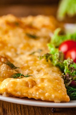 Özbek Doğu Tatar mutfağı, et ve suluguni ile cheburek peynirli sebze ve Yeşiller ahşap bir masa üzerinde beyaz bir tabak içinde.