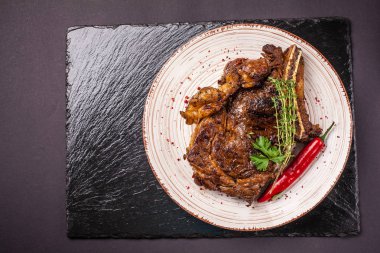 Sulu domuz Biftek soslu bir plaka seramik siyah bir arka plan üzerinde kırmızı biber ile büyük bir parçası. yan görünüm, kopya alanı, üstten görünüm