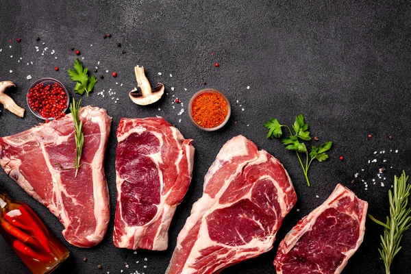 Et çiğ biftek bir siyah arka plan üzerine yalan sebze, domates, marasmade, mantar. arka plan görüntüsü. yan görünüm, kopya alanı, üstten görünüm