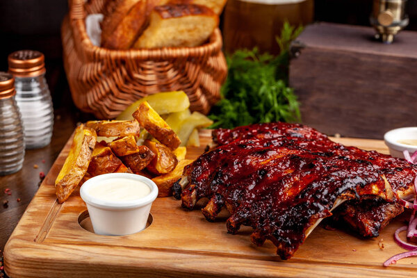 Fried ribs air fryer in marinade, with tartar sauce on a wooden board. With French fries in a rustic way and vegetables. concept of a beautiful serve in a restaurant or in a cafe.