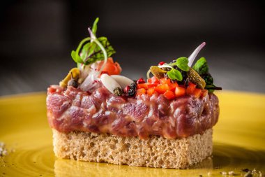 Haute mutfağının kavramı. Çiğ Dana ile Marine, Tartar sosu, makarna, ekmek, yeşil-sarı seramik tabak içinde mikro ile. Restoranda güzel hizmet.