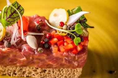 Haute mutfağının kavramı. Çiğ Dana ile Marine, Tartar sosu, makarna, ekmek, yeşil-sarı seramik tabak içinde mikro ile. Restoranda güzel hizmet.