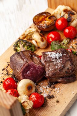 Orta pişmiş, ahşap bir tahta üzerinde ızgara sebzeli iki sulu biftek ile kızarmış. Hava Fritözler ile pişirilir. Akşam yemeği akşam koydu tabloda restoran tatil veya Doğum günü için. seçici odak