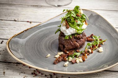 haşlanmış yumurta ile sulu biftek ve zeytin yağı, keçi peyniri salatası rucola büyük bir parçası bir plaka üzerinde yatıyor. Bir bardak kırmızı şarap geçerli. güzel bir yemek için bir restoran hizmet kavramı