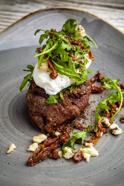 haşlanmış yumurta ile sulu biftek ve zeytin yağı, keçi peyniri salatası rucola büyük bir parçası bir plaka üzerinde yatıyor. Bir bardak kırmızı şarap geçerli. güzel bir yemek için bir restoran hizmet kavramı