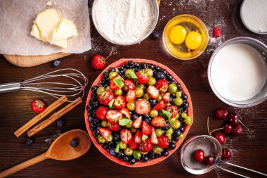 Orman çilek, çilek, Bektaşi, ahududu, kiraz ile Japon bisküvi bir pasta yapma süreci. Masaya malzemeler ve şekerleme stok yalan. üstten görünüm