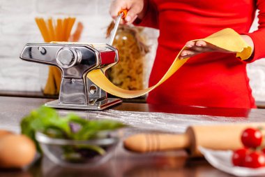 Adım adım. El ile işlem yapma Fettuccine makarna çeşitleri. Ev makarna makarna üreticisi ile. Un, semola di grano duro, yumurta, domates, fesleğen yalan ahşap bir masa üzerine. Tarifi.