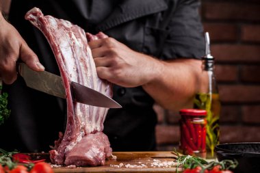 Et pişirme kavramı. Yalan çiğ sebze, kiraz, maydanoz, dereotu yanındaki ahşap bir masa üzerinde elinde bir bıçak tutan adam aşçı, kasap, sığır eti, kuzu, Dana, çiğ et keser.