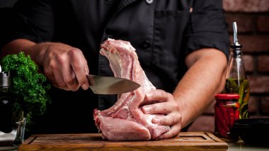 Et pişirme kavramı. Yalan çiğ sebze, kiraz, maydanoz, dereotu yanındaki ahşap bir masa üzerinde elinde bir bıçak tutan adam aşçı, kasap, sığır eti, kuzu, Dana, çiğ et keser.