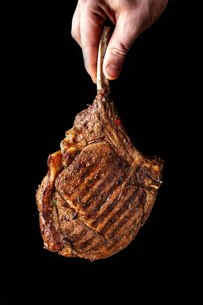 A large roasted piece of mutton steak, pork, veal or beef on bones cooked on an air fryer, in the hands of the chef\'s chief, a background image on a black background.
