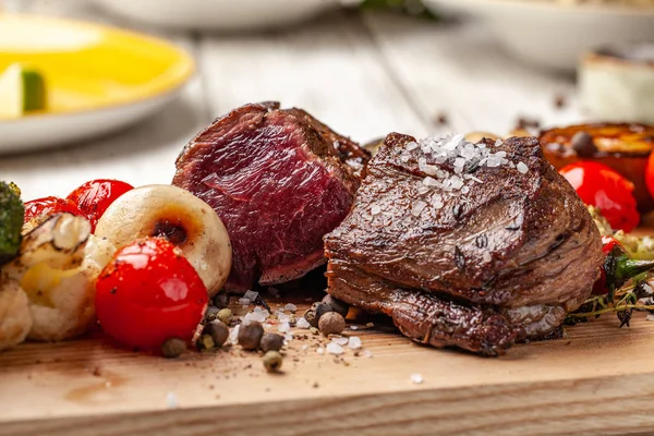 Orta pişmiş, ahşap bir tahta üzerinde ızgara sebzeli iki sulu biftek ile kızarmış. Hava Fritözler ile pişirilir. Akşam yemeği akşam koydu tabloda restoran tatil veya Doğum günü için. seçici odak