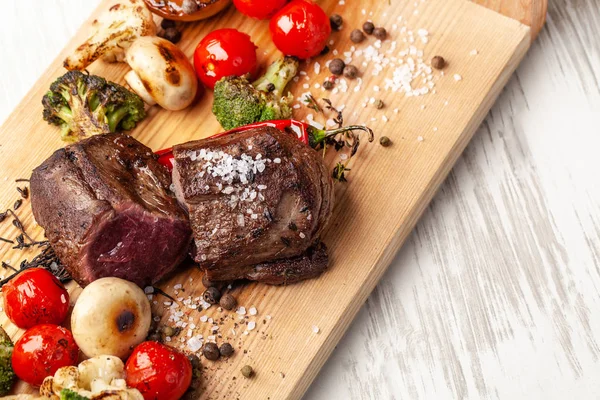 Orta pişmiş, ahşap bir tahta üzerinde ızgara sebzeli iki sulu biftek ile kızarmış. Hava Fritözler ile pişirilir. Akşam yemeği akşam koydu tabloda restoran tatil veya Doğum günü için. seçici odak