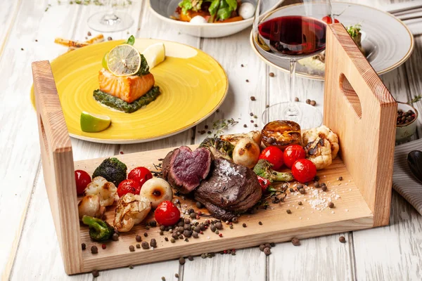 Orta pişmiş, ahşap bir tahta üzerinde ızgara sebzeli iki sulu biftek ile kızarmış. Hava Fritözler ile pişirilir. Akşam yemeği akşam koydu tabloda restoran tatil veya Doğum günü için. seçici odak