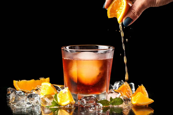 クール オレンジ アルコール カクテル バーでグラスの中の氷のボール アイス オレンジ ミント テーブルの上バーテンダーは彼の手で グラスにジュースを圧搾します — ストック写真