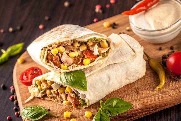 Burritos, kebab, shaurma wraps beef and vegetables on a black background and lies on a wooden board. Beef burrito, Mexican and oriental food.
