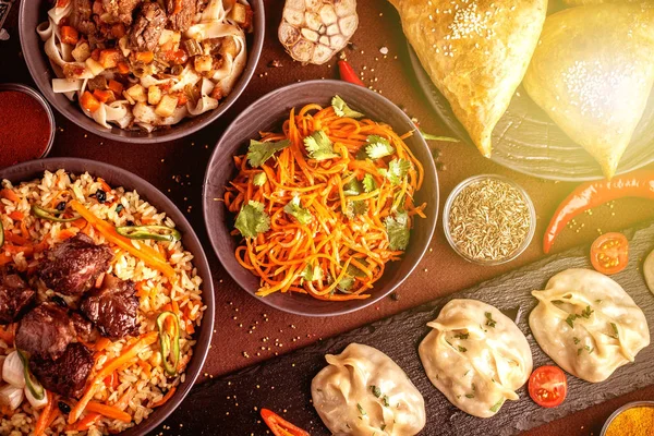 Assorted Uzbek food set, pilaf, samsa, lagman, manta and Korean carrots, Uzbek restaurant concept, Uzbek food feast. Festive, homemade lunch, dinner for the whole family. copy space, top view — Stock Image Assorted Uzbek Food Set Pilaf Samsa Lagman Manta Korean Carrots Stock Photo
