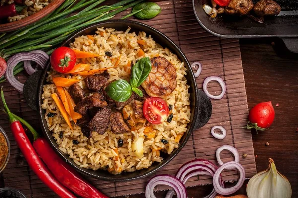 Doğu mutfağı kavramı. Ev yapımı özbek pilavı kuzu üzerinden dökme demir tencere içinde servis. Kopya alanı.