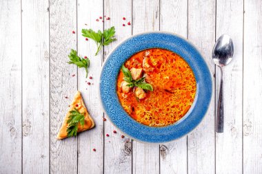 İtalyan Avrupa mutfağı. Deniz ürünleri, somon ve alabalık, mavi bir tabak içinde sebzeli baharatlı balık çorbası. restoranda masada bir bardak beyaz şarap var. Kopya alanı, seçici odak