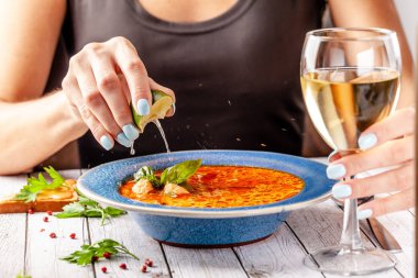 İtalyan mutfağı. Restoranda kız deniz ürünleri ve somon balık çorbası yiyor çorbanın içine kireç sıkar ve beyaz şarap içiyor. Kopya alanı, seçici odak