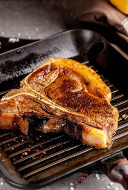 Amerikan mutfağı. Et pişirme şey kavramı. Peccias, kekik ve sarımsak ile ızgara tava T-bone biftek kızarmış bir parçası yatıyor.