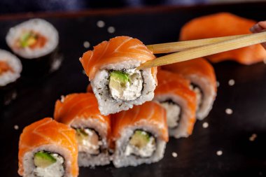 Japon ve Çin mutfağı kavramı. Restorandaki kızda ahşap yemek çubukları, suşi ve rulo var..