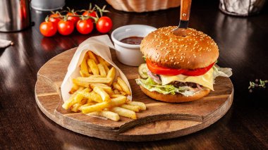 İtalyan mutfağı kavramı. İtalyan burger patates kızartması bir ahşap tahta ve bir bardak köpük ile hafif bira. Bir restoranda bir burger hizmet bir bıçak ile.