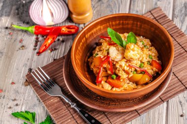 İspanya mutfağı kavramı. Paella deniz ürünleri ve karides, bir kil plaka yeşil bezelye ile. Bir kadeh iyi şarap tablodur.