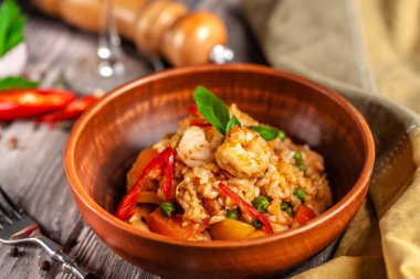 İspanya mutfağı kavramı. Paella deniz ürünleri ve karides, bir kil plaka yeşil bezelye ile. Bir kadeh iyi şarap tablodur.