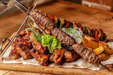 Gürcü mutfağı kavramı. Et kurulu ile Kebab, ızgara domuz pirzola, lulya Kebap ve şiş kebap. Izgara patates kızartması ve ızgara sebzeler. Ahşap bir gemide yem et.