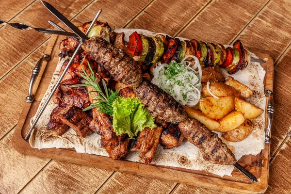 Gürcü mutfağı kavramı. Et kurulu ile Kebab, ızgara domuz pirzola, lulya Kebap ve şiş kebap. Izgara patates kızartması ve ızgara sebzeler. Ahşap bir gemide yem et.