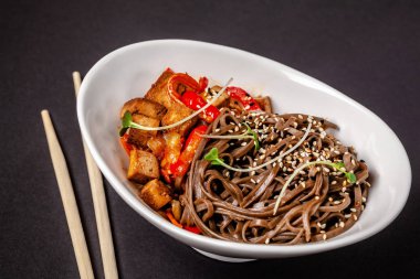 Asya mutfağı kavramı. Buğday noodle ile sebze ve tofu. Havuç, biber, beyaz ve siyah susam. Japonca veya Çince yemek.