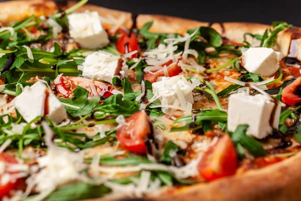 The concept of Italian cuisine. Real Italian pizza on a thin cake with large sides on a black background. Close up. Background image.