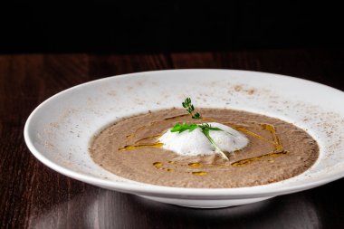 İtalyan mutfağı kavramı. Mantar çorbası krem ve baharatlarla zeytinyağı ile mantar püresi. Bir bardak kırmızı şarap yanındaki tablodur. Restoranda yemekler sunan güzel.