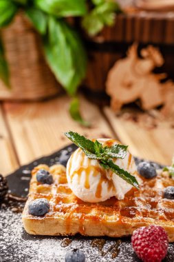 Bir kepçe dondurma, taze çilek ahududu, böğürtlen, yaban mersini ve nane ile Belçika Waffle. Krema şeker ile silkeledi ve karamel sos dökülür. seçici odak