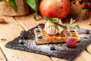 Bir kepçe dondurma, taze çilek ahududu, böğürtlen, yaban mersini ve nane ile Belçika Waffle. Krema şeker ile silkeledi ve karamel sos dökülür. seçici odak