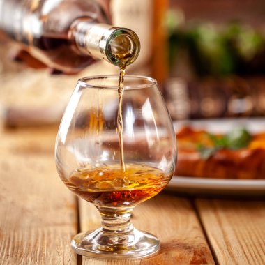 Gürcü Restoran kavramı. Bir kız Gürcü bir şişe brendi cam içine dökülen. Ahşap bir masaya hachipuri olduğunu