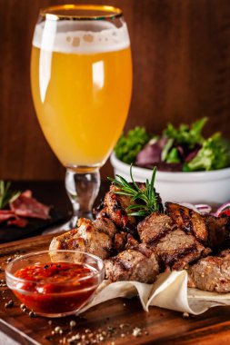 Gürcü mutfağı kavramı. Sığır eti, domuz eti ve tavuk kebap ile büyük bir ahşap tahta. Barbekü sos ve ketçap. Arka planda bir light bira köpük bardak