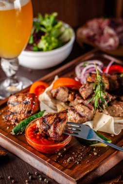 Gürcü mutfağı kavramı. Sığır eti, domuz eti ve tavuk kebap ile büyük bir ahşap tahta. Barbekü sos ve ketçap. Arka planda bir light bira köpük bardak
