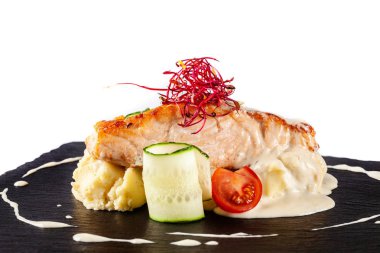 Biftek kırmızı balık somon veya patates püresi, cherry domates, salatalık ve kremalı sos bir garnitür ile alabalık balık. Modern restoran siyah arduvaz yazı tahtası üzerinde hizmet veren.