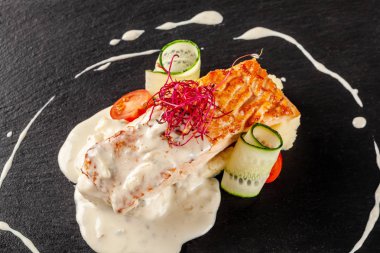 Biftek kırmızı balık somon veya patates püresi, cherry domates, salatalık ve kremalı sos bir garnitür ile alabalık balık. Modern restoran siyah arduvaz yazı tahtası üzerinde hizmet veren.