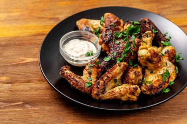 Baharat köri ve ahşap arka plan üzerinde siyah bir tabakta maydanoz ile Meksika pişmiş tavuk kanatları. yan görünüm, kopya alanı, üstten görünüm