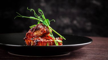 Amerikan mutfağı kavramı. Domuz kaburga, pişmiş ve barbekü sosuna sırlı kavrulmuş. Siyah plaka restoran yemekleri susam ve mikro ile yeşil hizmet. Bir bardak kırmızı şarap yanında.