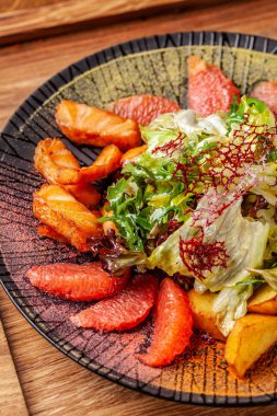 2019 yılında modern Arap mutfağı. Asya salata bal soslu kızarmış somon, avakado, greyfurt ve salata karıştırın. Oryantal baharatlar ile siyah bir tabak içinde bir restoranda yemekler sunan.