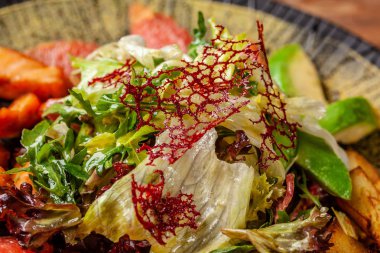 2019 yılında modern Arap mutfağı. Asya salata bal soslu kızarmış somon, avakado, greyfurt ve salata karıştırın. Oryantal baharatlar ile siyah bir tabak içinde bir restoranda yemekler sunan.