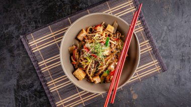 Japon mutfağı kavramı. Çin Eriştesi tavuk, ızgara sebzeler ve tofu unagi sos ile. Bir plaka üzerinde bir bambu hasır Restaurant'ta Asya yemekleri sunan. Üstten görünüm, kopya alanı